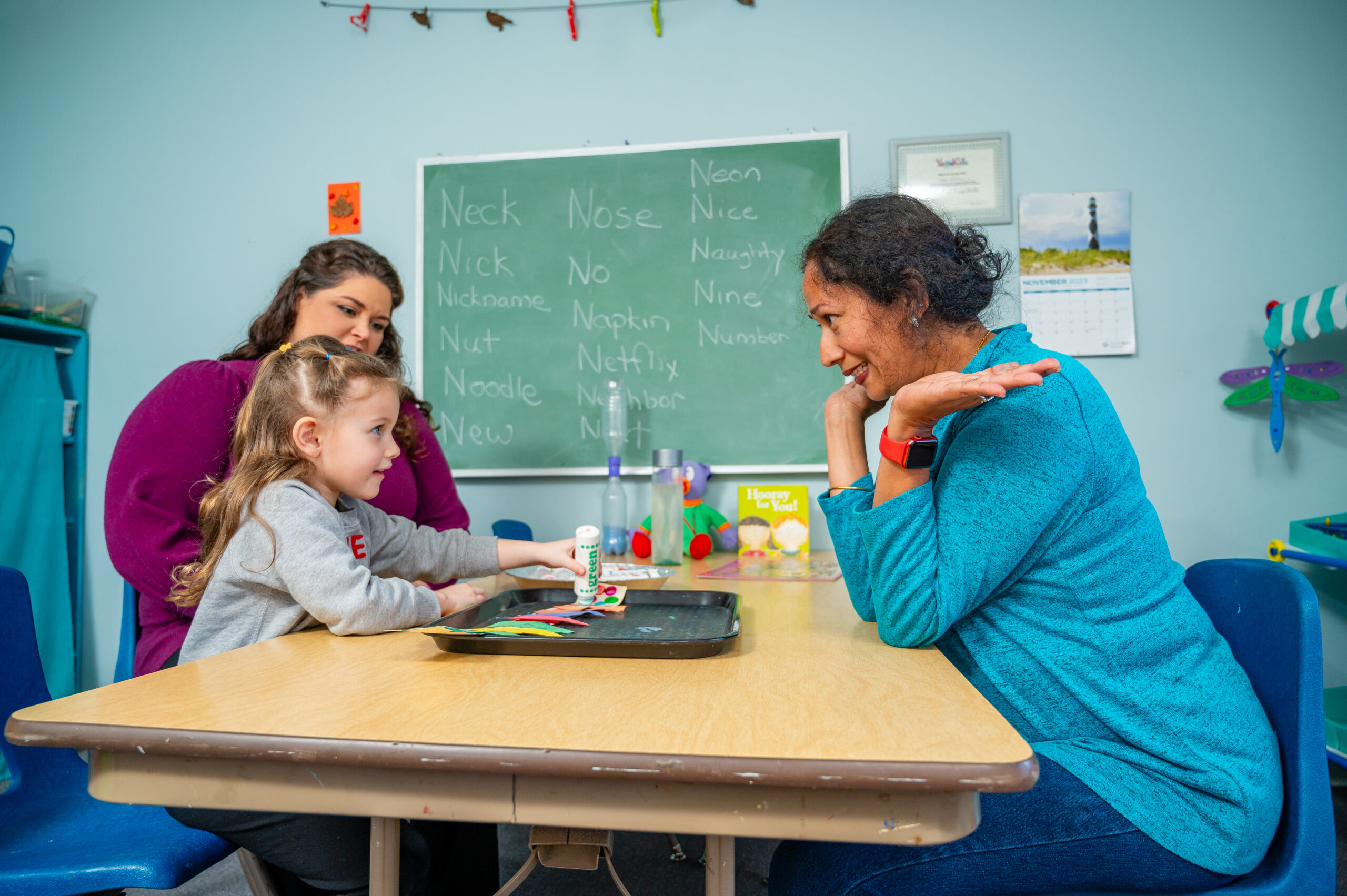 Two teachers and a young girl do arts and crafts